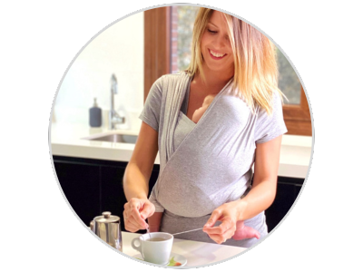 imagen de una mama porteando a un recien nacido en la camiseta quokkababy en la que se muestra la ergonomia para el bebe mientras la madre realiza las tareas de casa
